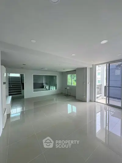 Spacious modern living room with large windows and glossy tiled floors, perfect for natural light lovers.