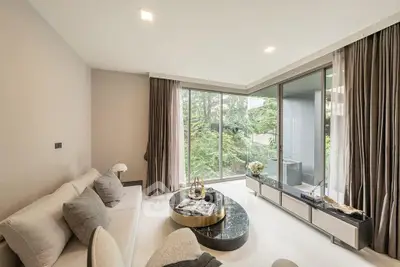 Luxurious living room with floor-to-ceiling windows and modern decor, offering a serene garden view.
