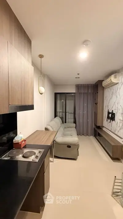 Modern living room with sleek kitchen and cozy seating area in stylish apartment.