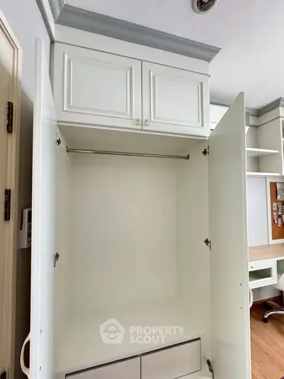 Spacious white built-in wardrobe with open doors showcasing ample storage space.