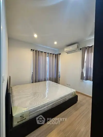 Cozy bedroom with modern design, featuring a comfortable bed and natural light from large windows.