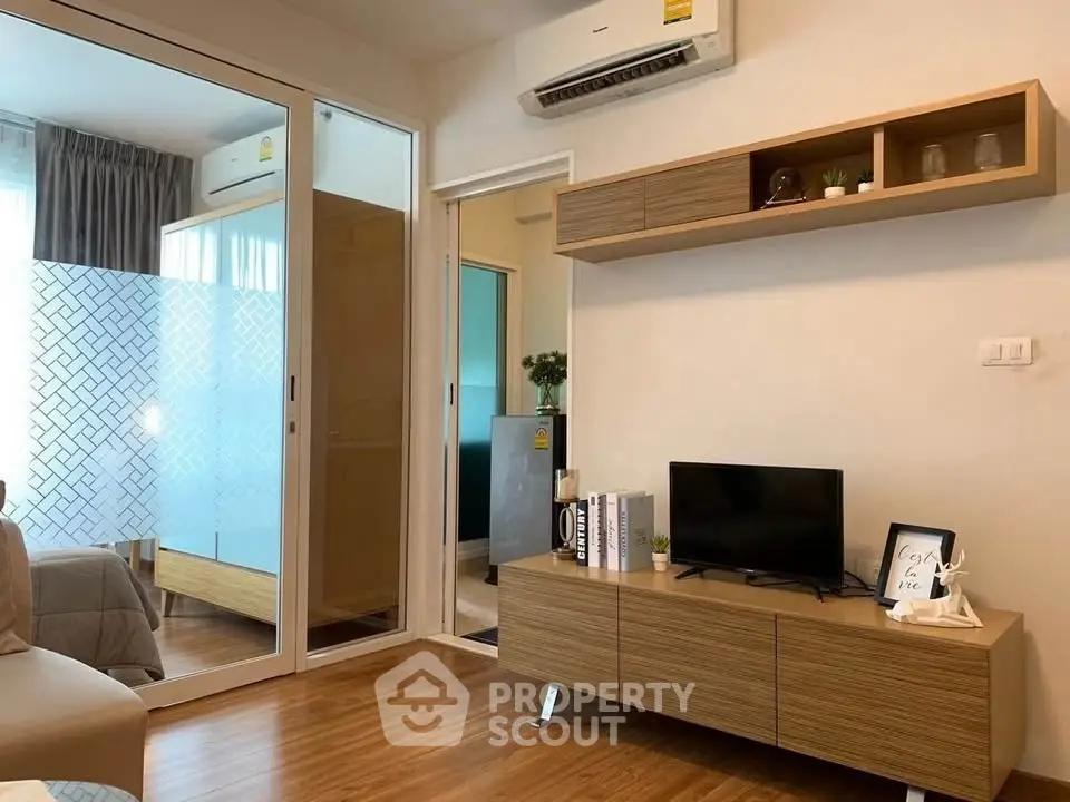 Modern living room with wooden flooring, sleek TV stand, and air conditioning unit.