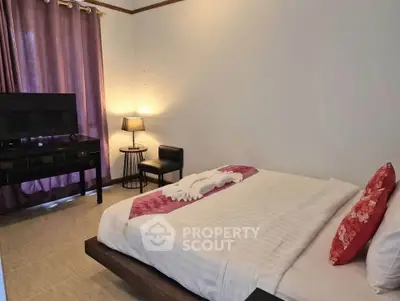 Cozy bedroom with elegant decor and natural light, featuring a stylish bed and modern TV setup.
