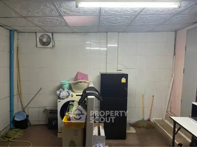 Utility room with washing machine and refrigerator in a tiled basement.