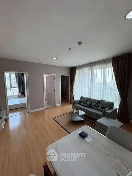 Spacious living room with modern decor and large windows offering city views.