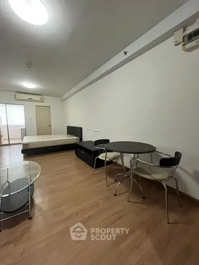 Spacious studio apartment with modern furnishings and wooden flooring, featuring a cozy dining area and comfortable bed.