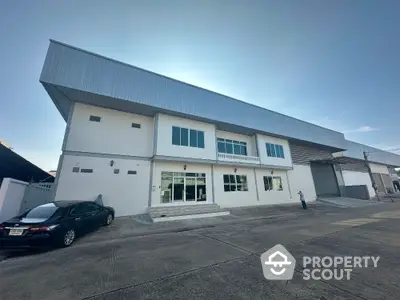 Modern industrial building with spacious parking area and sleek exterior design