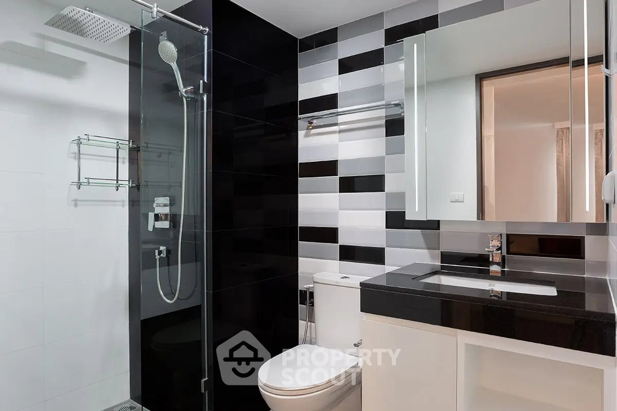 Modern bathroom with sleek black and white tiles, glass shower, and contemporary fixtures.