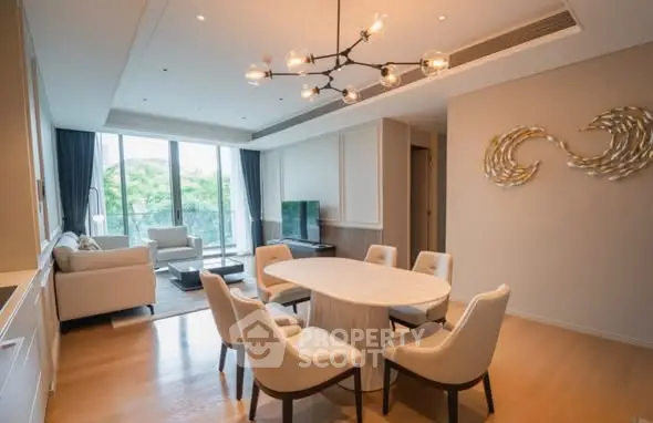 Elegant living room with modern decor and large windows offering a lush green view.
