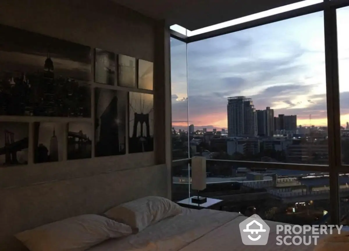 Luxurious bedroom with stunning city view at sunset, modern decor and large windows.