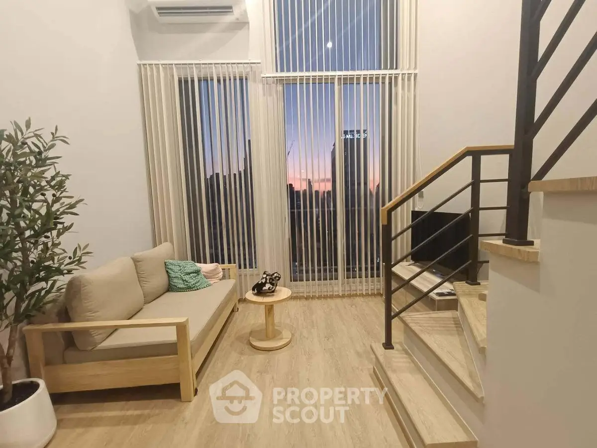 Modern living room with high ceilings, large windows, and sunset city view, featuring stylish furniture and wooden flooring.