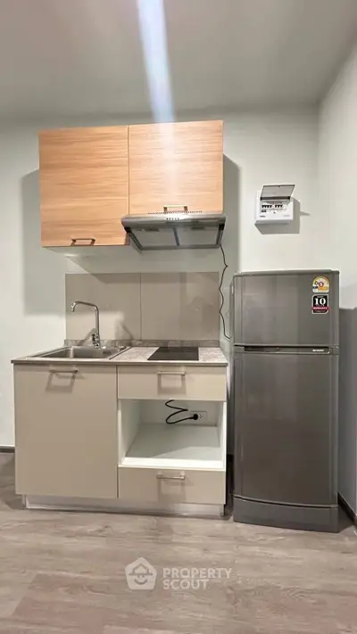 Modern compact kitchen with sleek cabinets and stainless steel fridge, perfect for urban living.