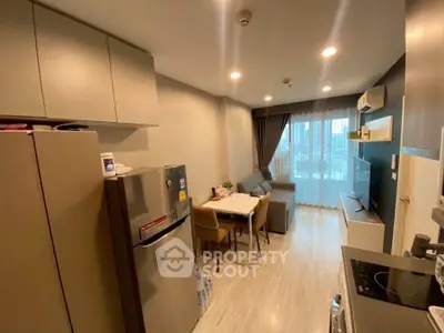 Modern living room with open kitchen, cozy seating, and large window offering city views.