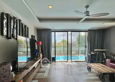 Spacious living room with pool view, modern decor, and large TV, perfect for relaxation and entertainment.