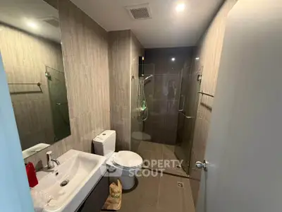 Modern bathroom with glass shower and sleek fixtures in contemporary home.