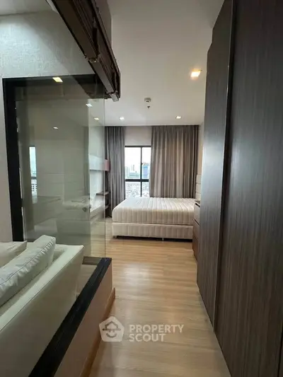 Modern bedroom with glass partition and city view, featuring sleek wood finishes and cozy ambiance.