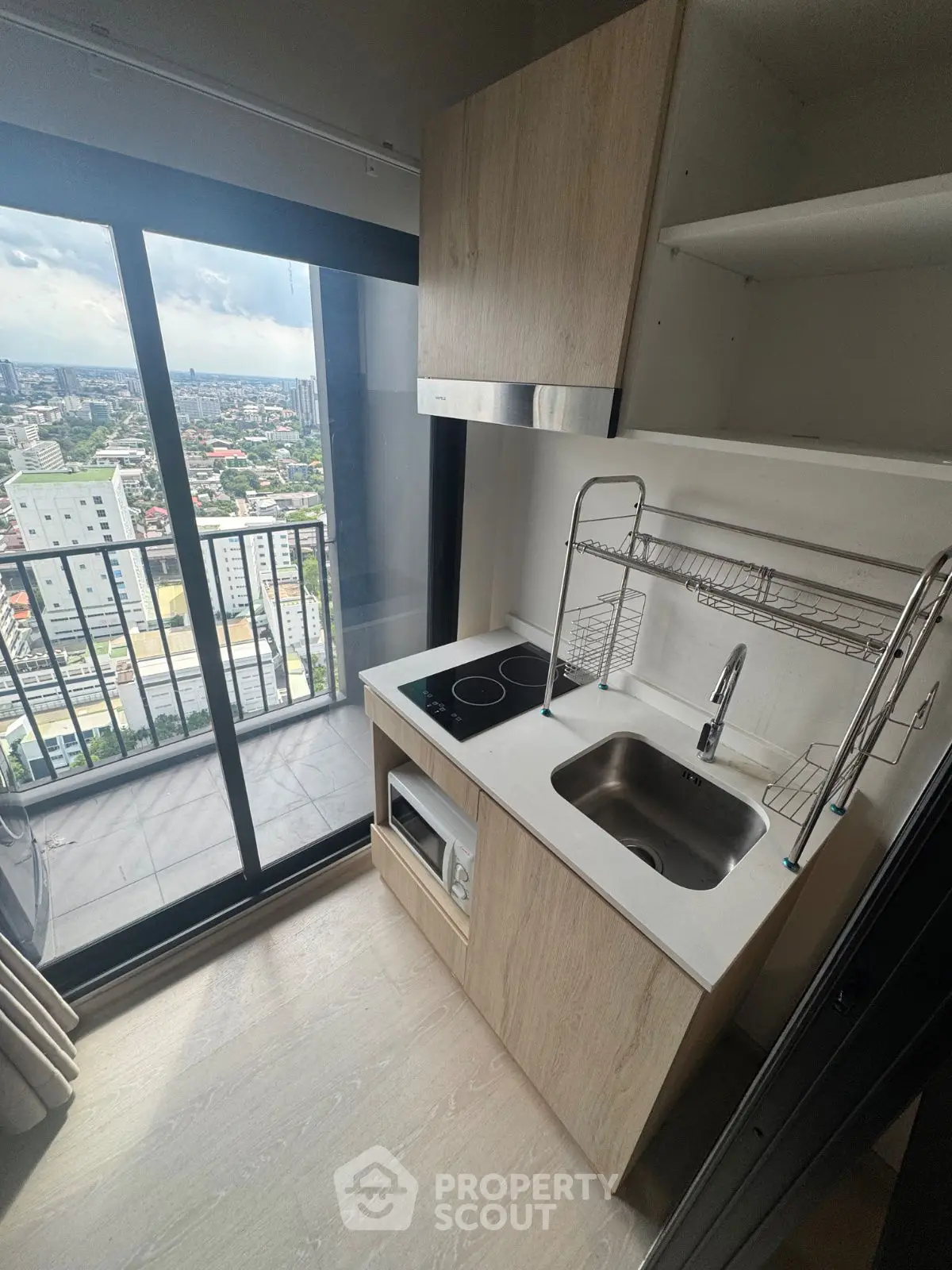 Modern compact kitchen with city view from high-rise balcony