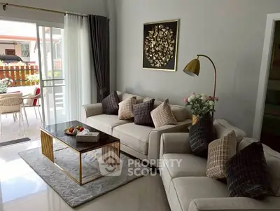 Elegant living room with modern decor, plush sofas, and a stylish coffee table, opening to a bright patio area.