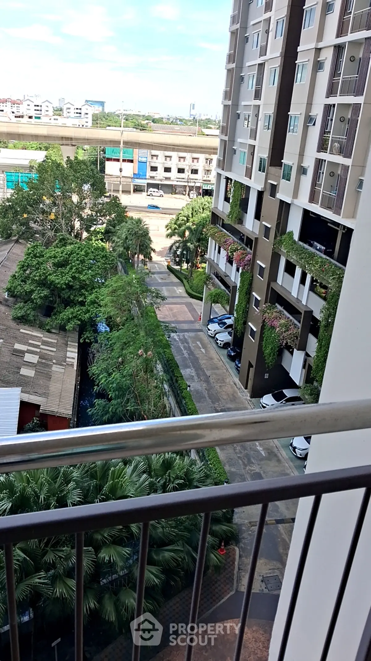 Modern urban apartment view with lush greenery and parking area
