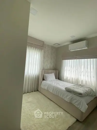 Cozy bedroom with single bed, soft lighting, and air conditioning.