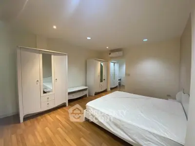 Spacious bedroom with elegant white furniture and wooden flooring