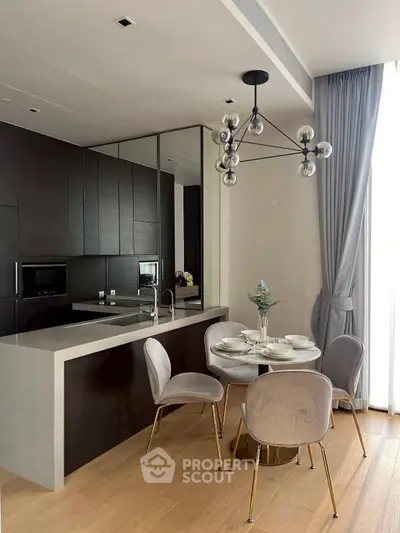 Modern kitchen with sleek black cabinetry, elegant dining area, and stylish lighting fixture.