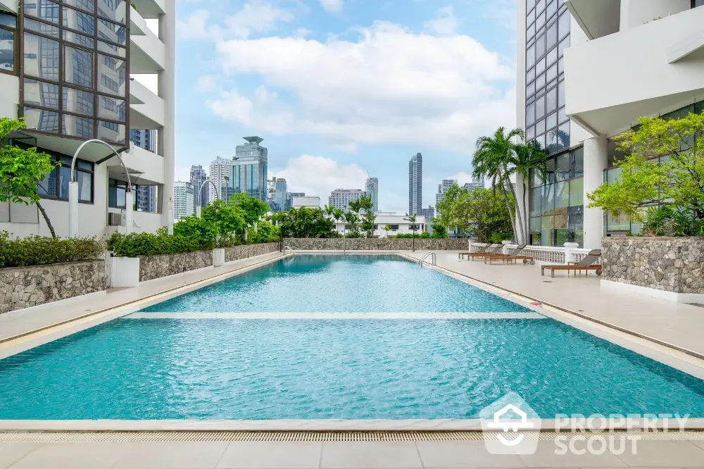 Luxurious condominium pool with city skyline view and lush greenery.