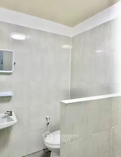 Modern minimalist bathroom with sleek tiles and compact fixtures.