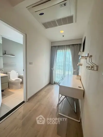 Modern study room with desk and bathroom view in a bright apartment