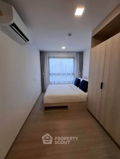 Modern bedroom with minimalist design, featuring a cozy bed, built-in wardrobe, and air conditioning.