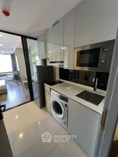 Modern kitchen with sleek appliances and washing machine in compact layout