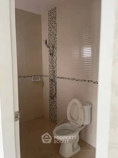 Modern bathroom with tiled walls and toilet in a real estate property.