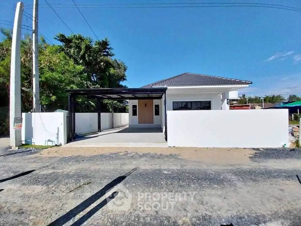 Modern single-story house with carport and minimalist design under clear blue sky.
