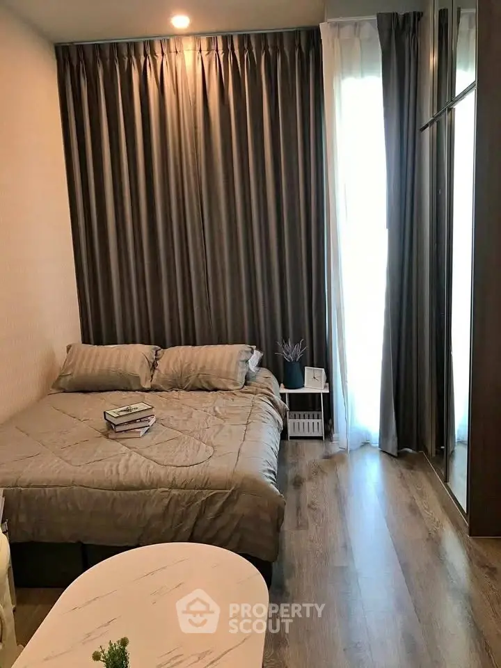 Cozy bedroom with elegant curtains and wooden flooring, perfect for relaxation.