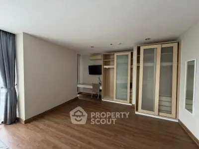 Spacious modern room with wooden flooring and built-in storage, ideal for versatile living.