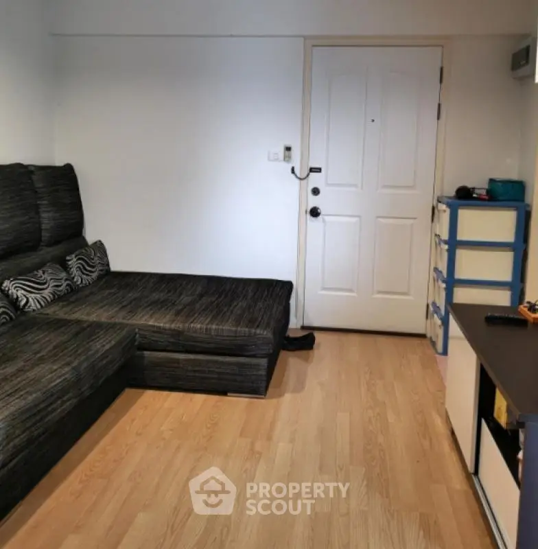 Cozy living room with modern sofa and wooden flooring in a compact apartment.