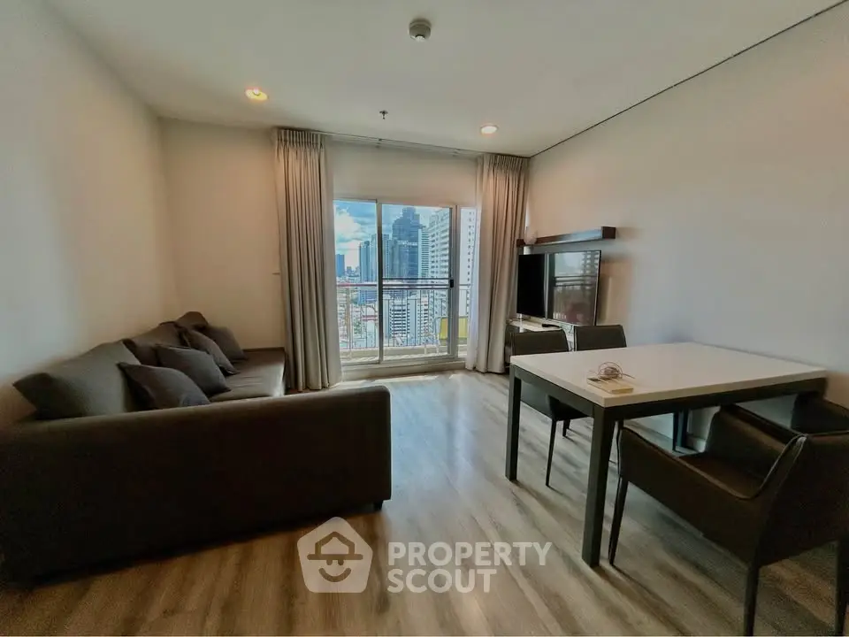 Modern living room with city view, featuring sleek furniture and large windows for natural light.