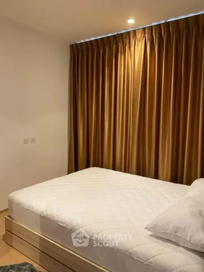 Cozy bedroom with elegant curtains and comfortable bed in modern apartment.