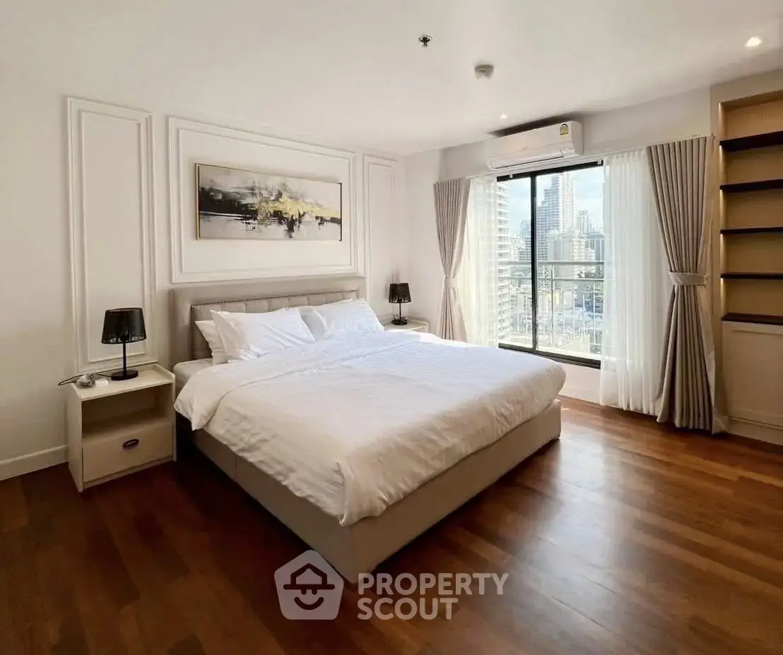 Spacious bedroom with city view, elegant decor, and natural light in modern apartment.