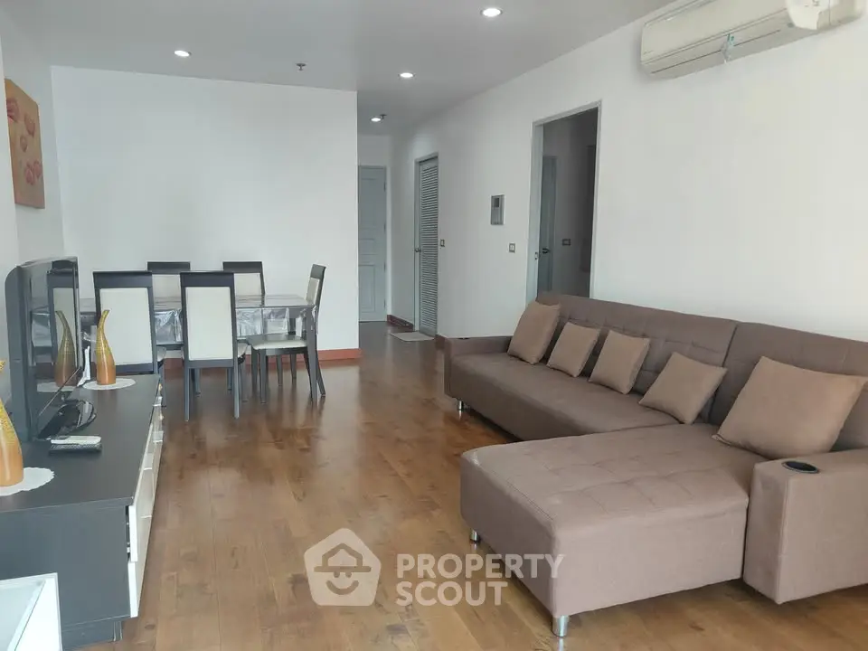 Spacious living room with modern furniture and wooden flooring in a stylish apartment.