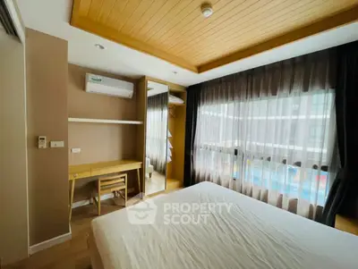 Cozy bedroom with large window and wooden ceiling accents