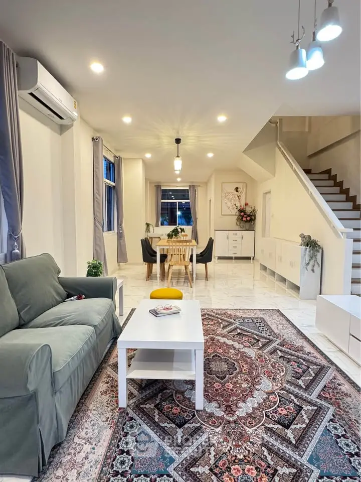 Spacious living room with elegant decor and open dining area, featuring modern lighting and cozy seating.