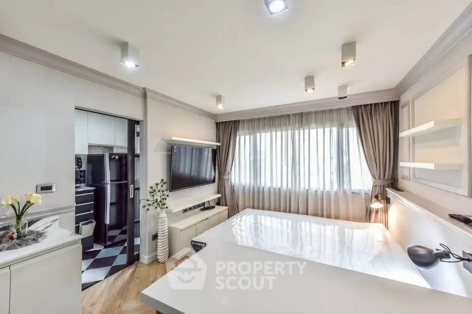 Modern living room with sleek design and large window, featuring a wall-mounted TV and stylish decor.