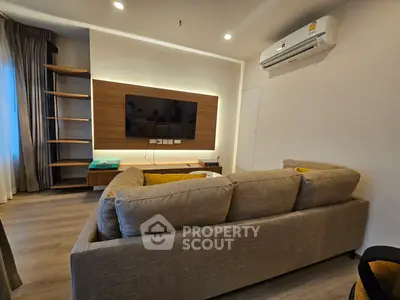 Modern living room with cozy sofa, wall-mounted TV, and stylish shelving unit.
