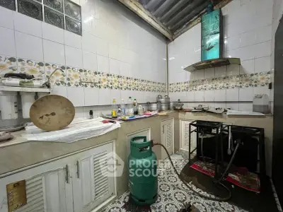 Rustic kitchen with gas stove and traditional decor, featuring tiled backsplash and patterned floor.