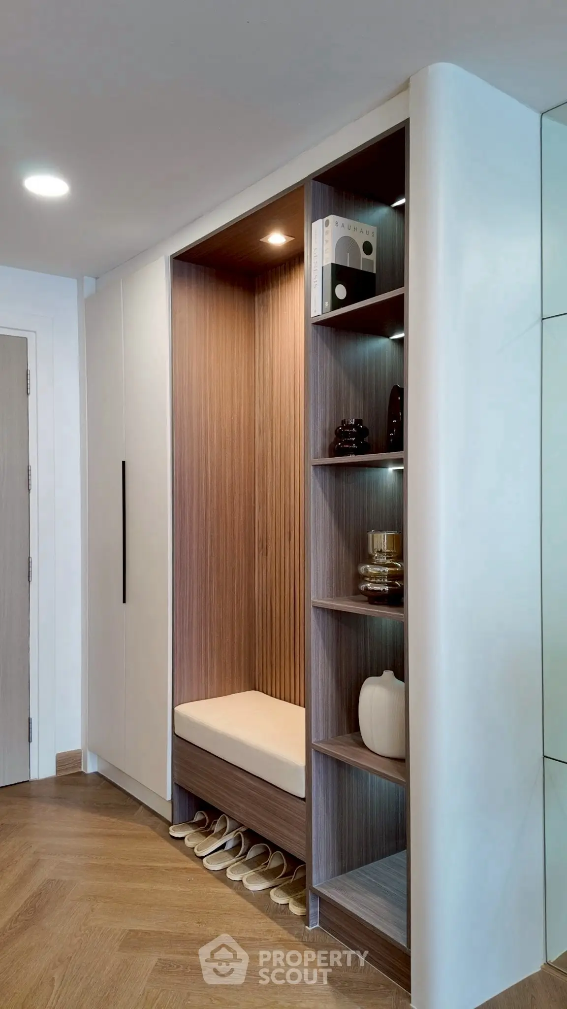 Modern entryway with built-in storage and seating, featuring elegant wood paneling and decorative shelving.
