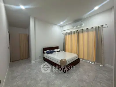 Spacious bedroom with modern design and ample natural light, featuring a comfortable bed and stylish decor.