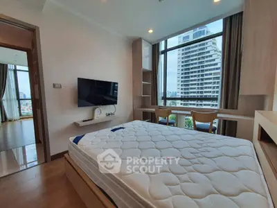 Spacious bedroom with large window offering city views, featuring modern furnishings and ample natural light.