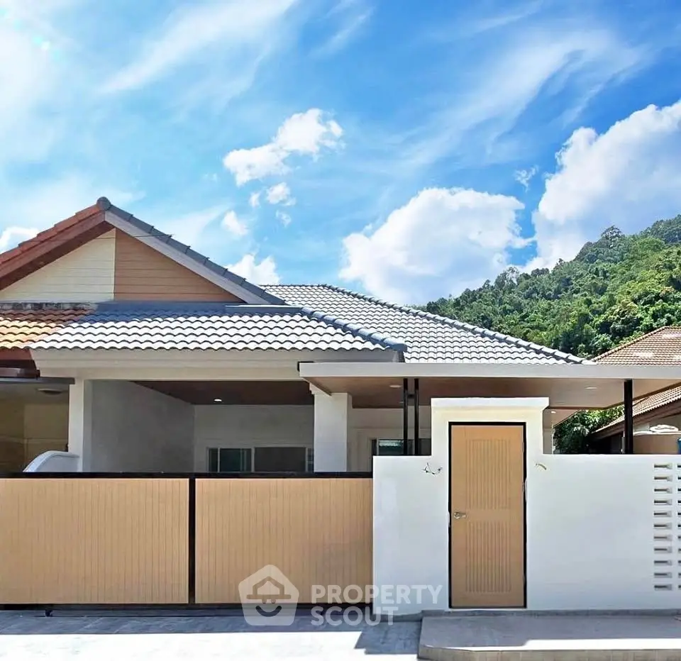 Charming single-story house with modern design and mountain backdrop, perfect for serene living.