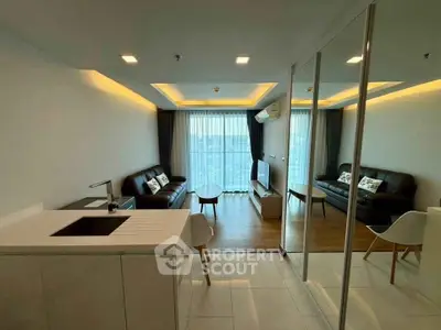Modern living room with open kitchen, featuring sleek furniture and large windows for natural light.